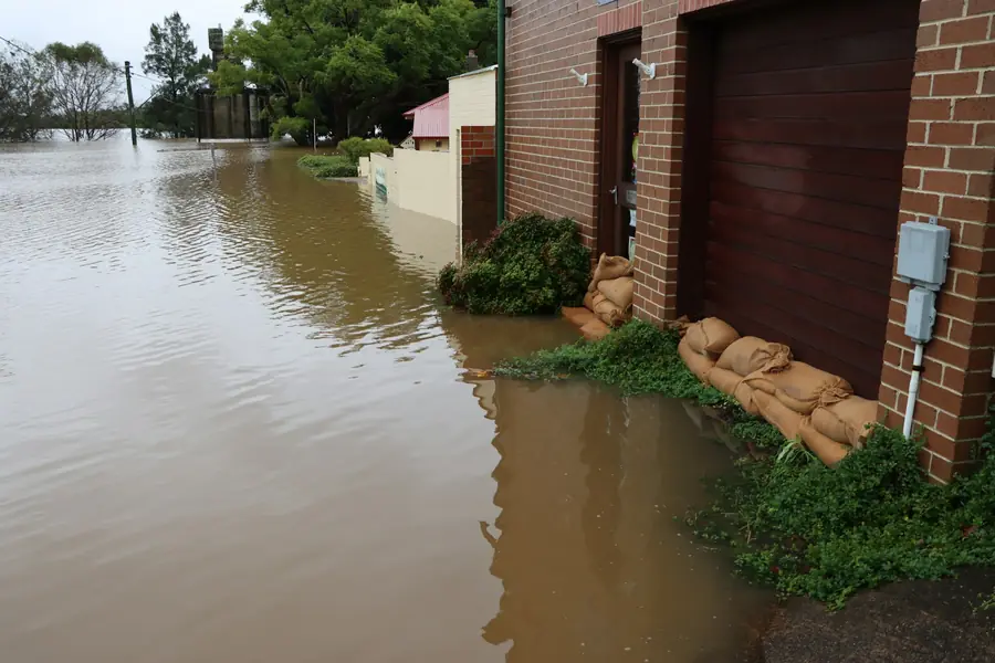 Floodwater against a brick home with sandbags at the door