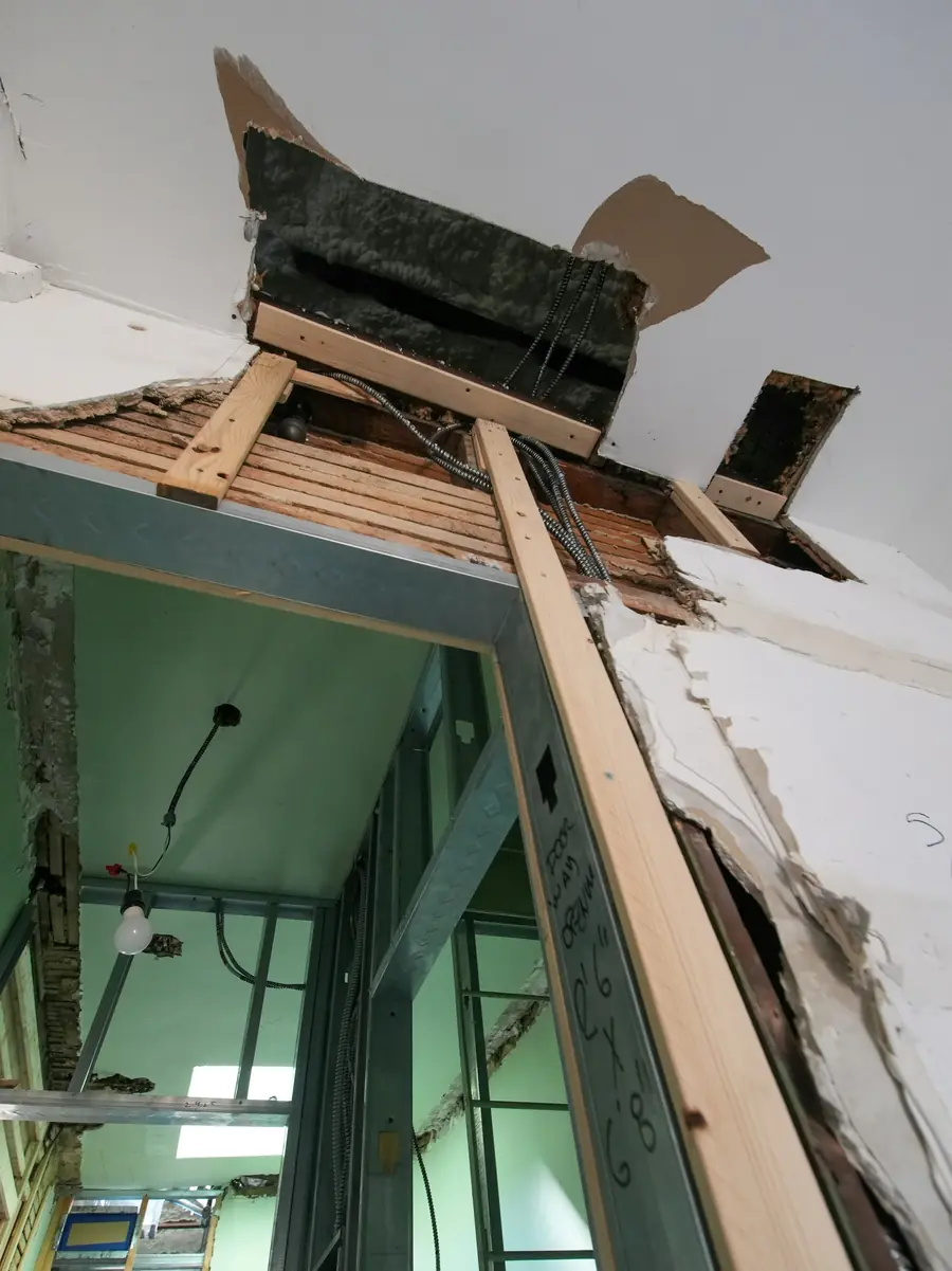 Opened ceiling showing damaged framing and exposed wiring